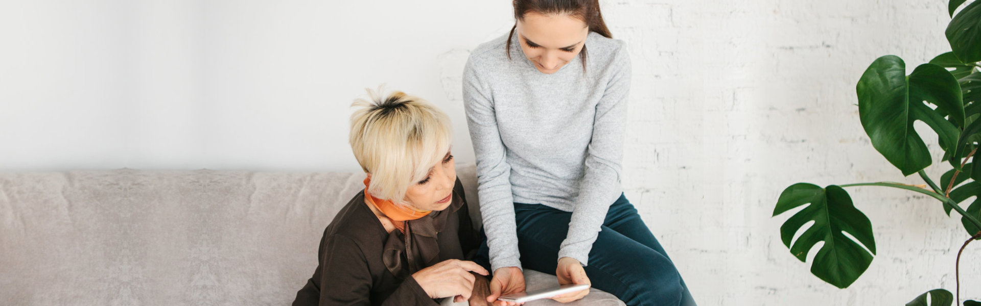 young woman helping senior woman navigate tablet