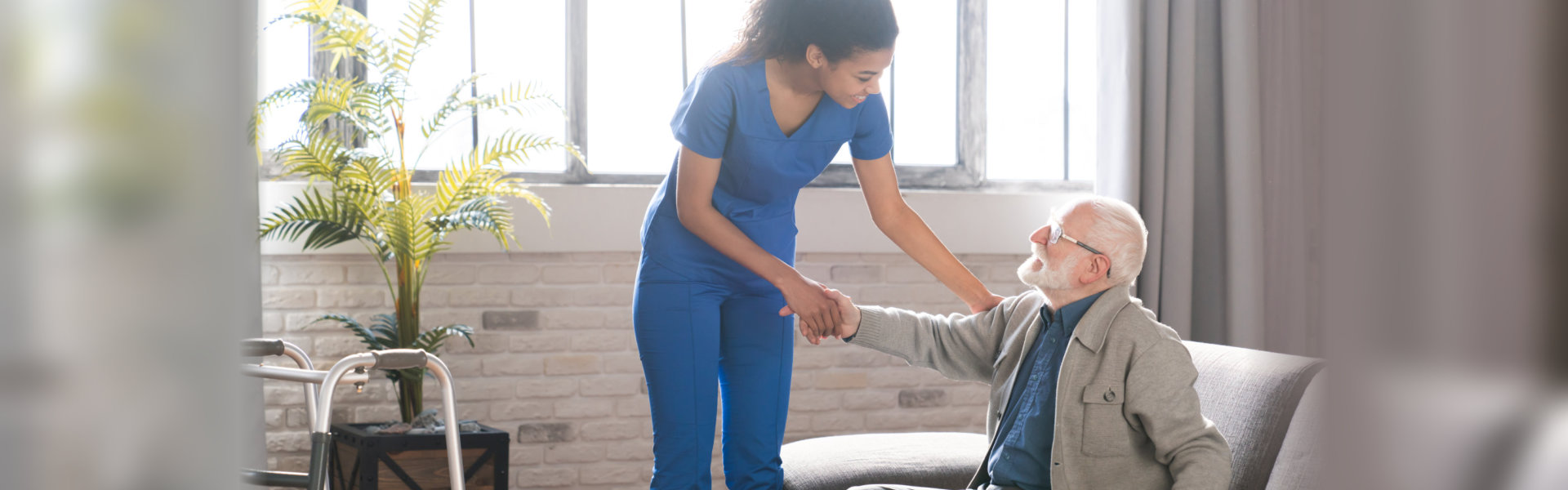 a young woman in blue scrubs helping an elderly man