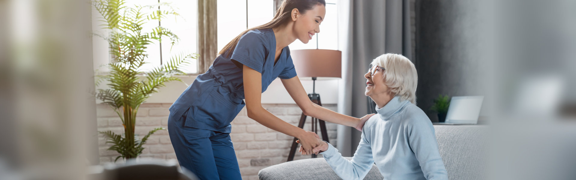 a young woman in blue scrubs assisting an elderly woman